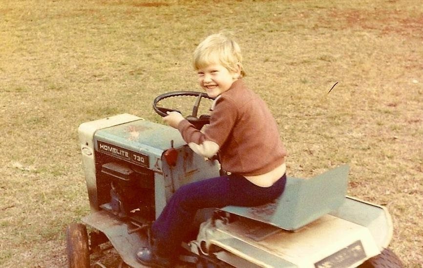 Jake Snyman as a child sitting on a mower